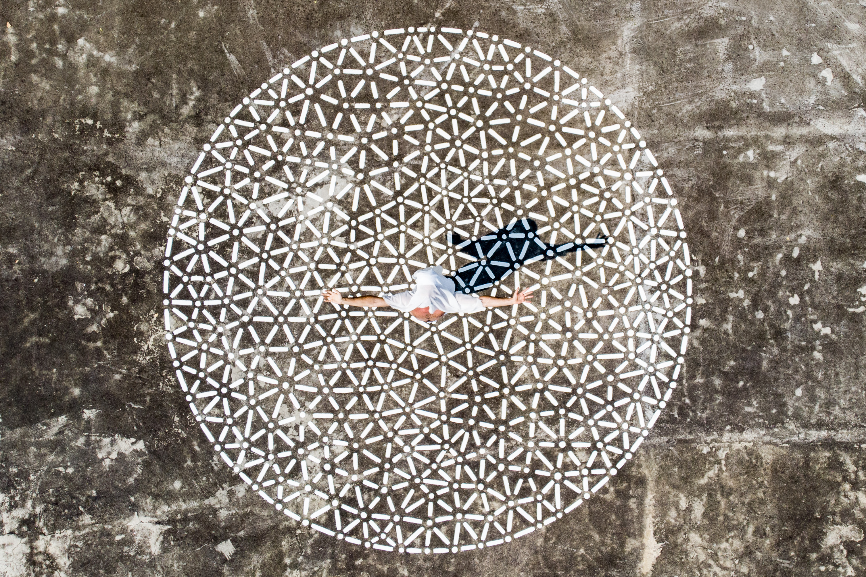 White dots and lines form a large circle around a small central figure on a textured gray-brown background.