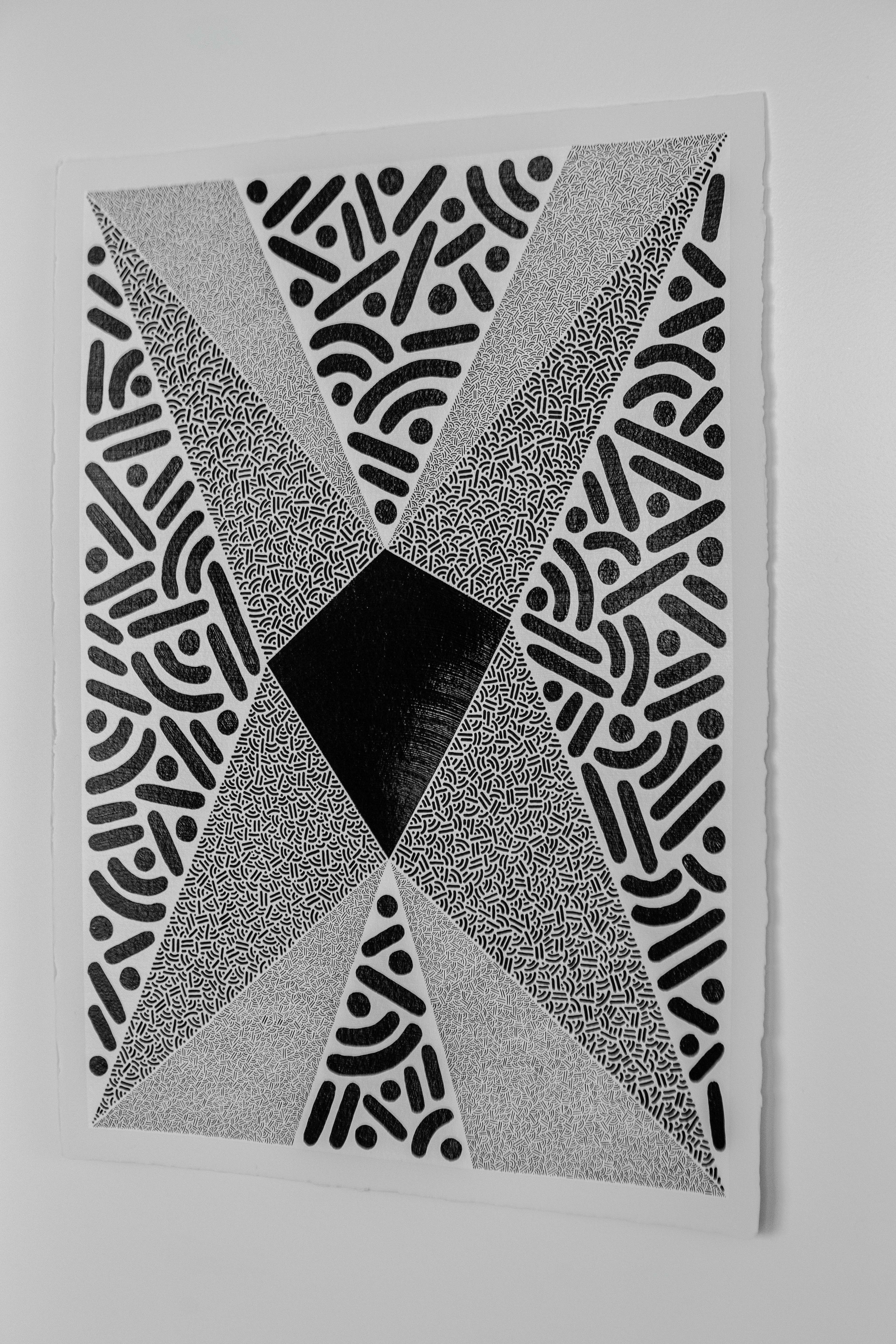 Singularity: Black-and-white geometric artwork with four gray triangles meeting at a dark central diamond, displayed on a wall.