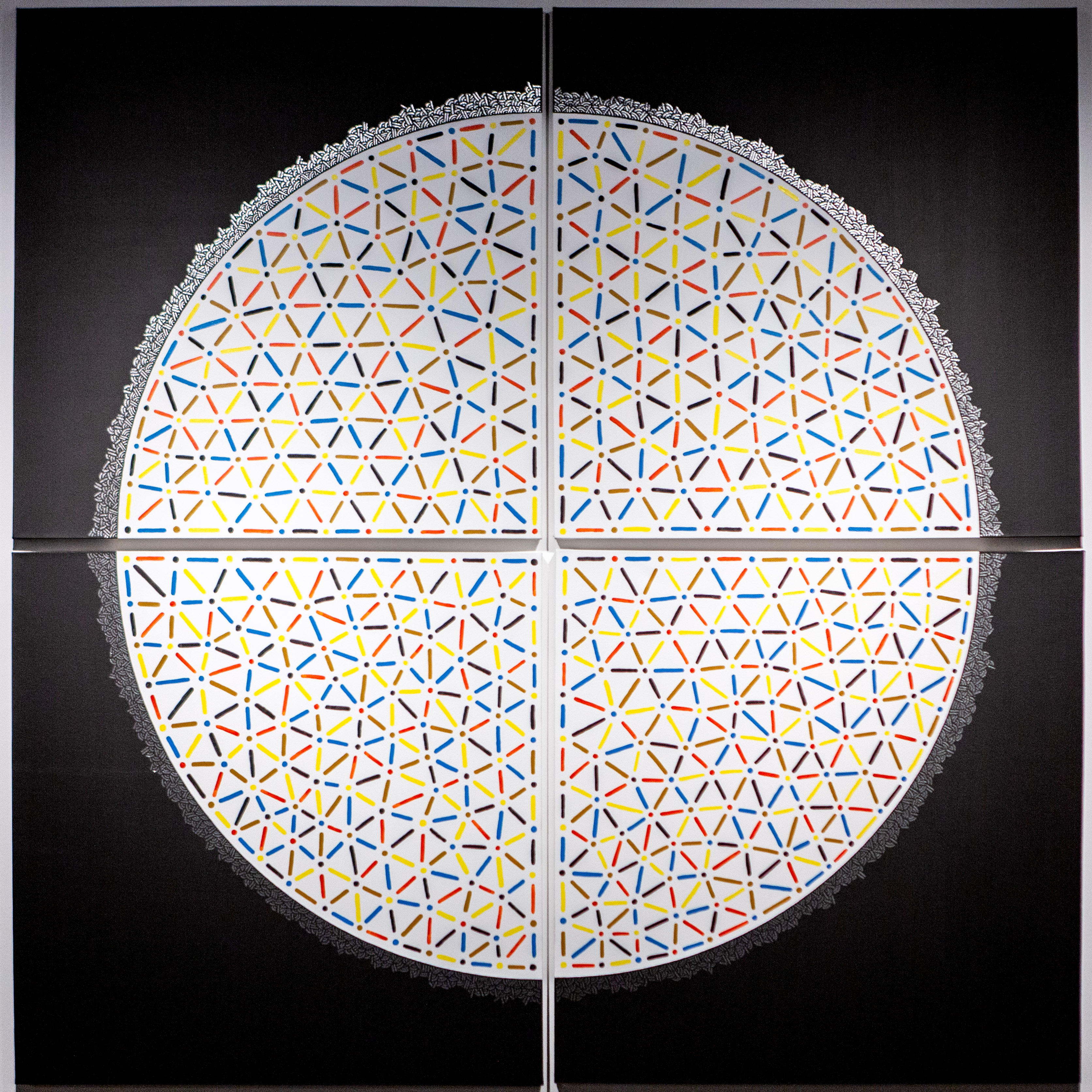 Large circular artwork divided into four panels and filled with multicolored triangular patterns.