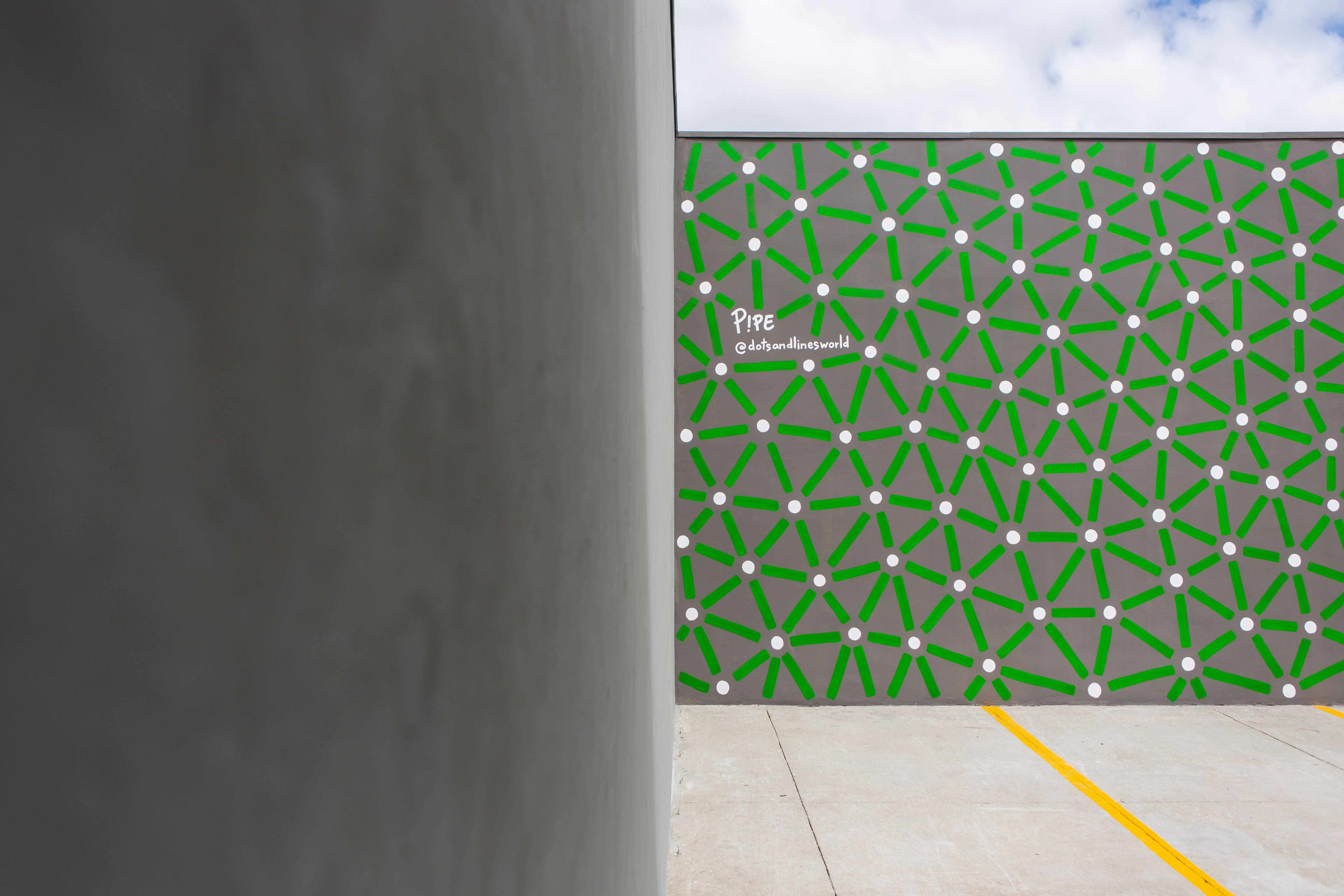Roots: View past a gray column toward green connecting lines and pale dots on a courtyard wall.