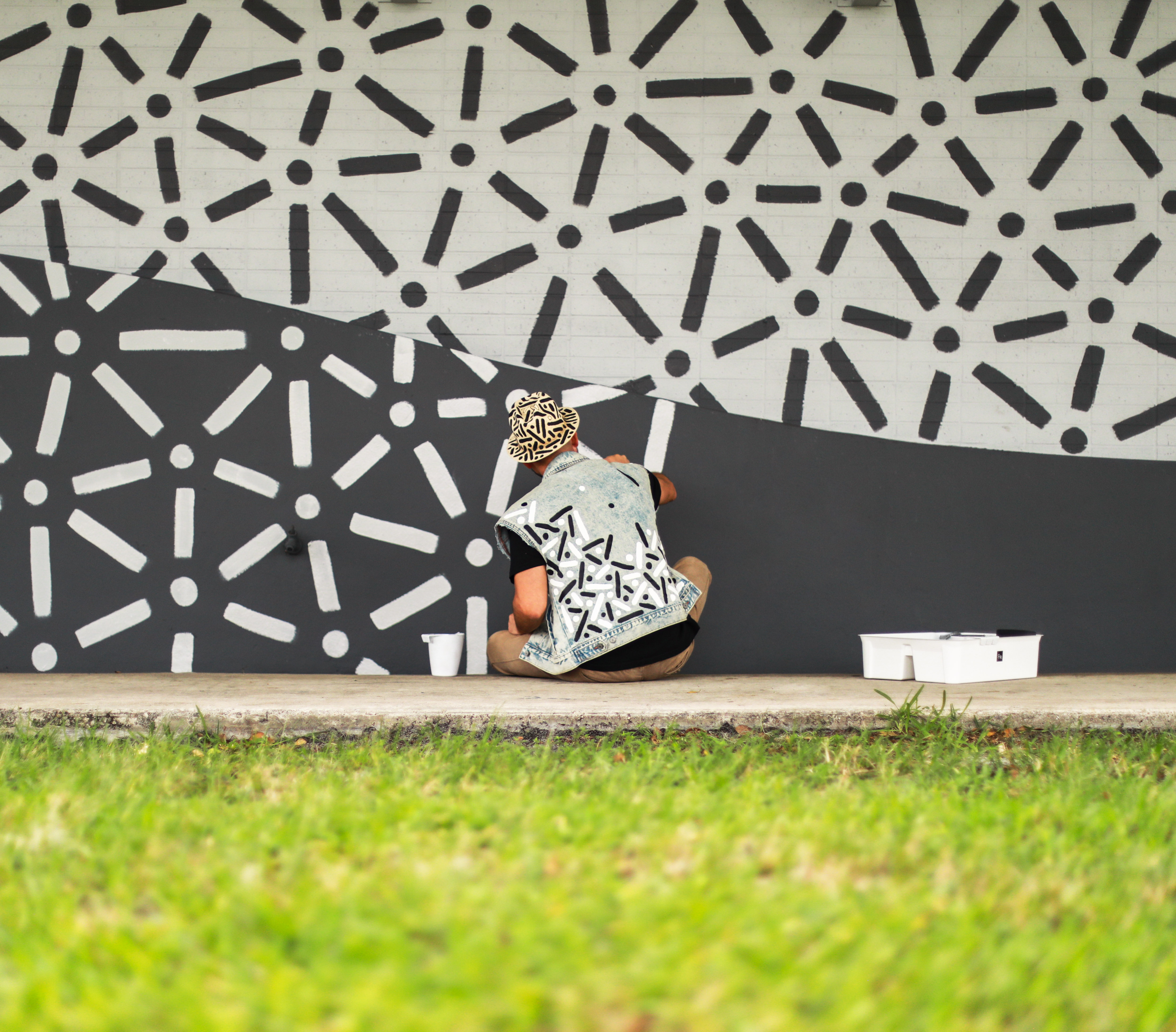 Artist Pipe Yanguas painting his gray-scale dots-and-lines mural, “The Wave,” on the exterior wall of ArtServe in Fort Lauderdale, Florida, in 2022.
