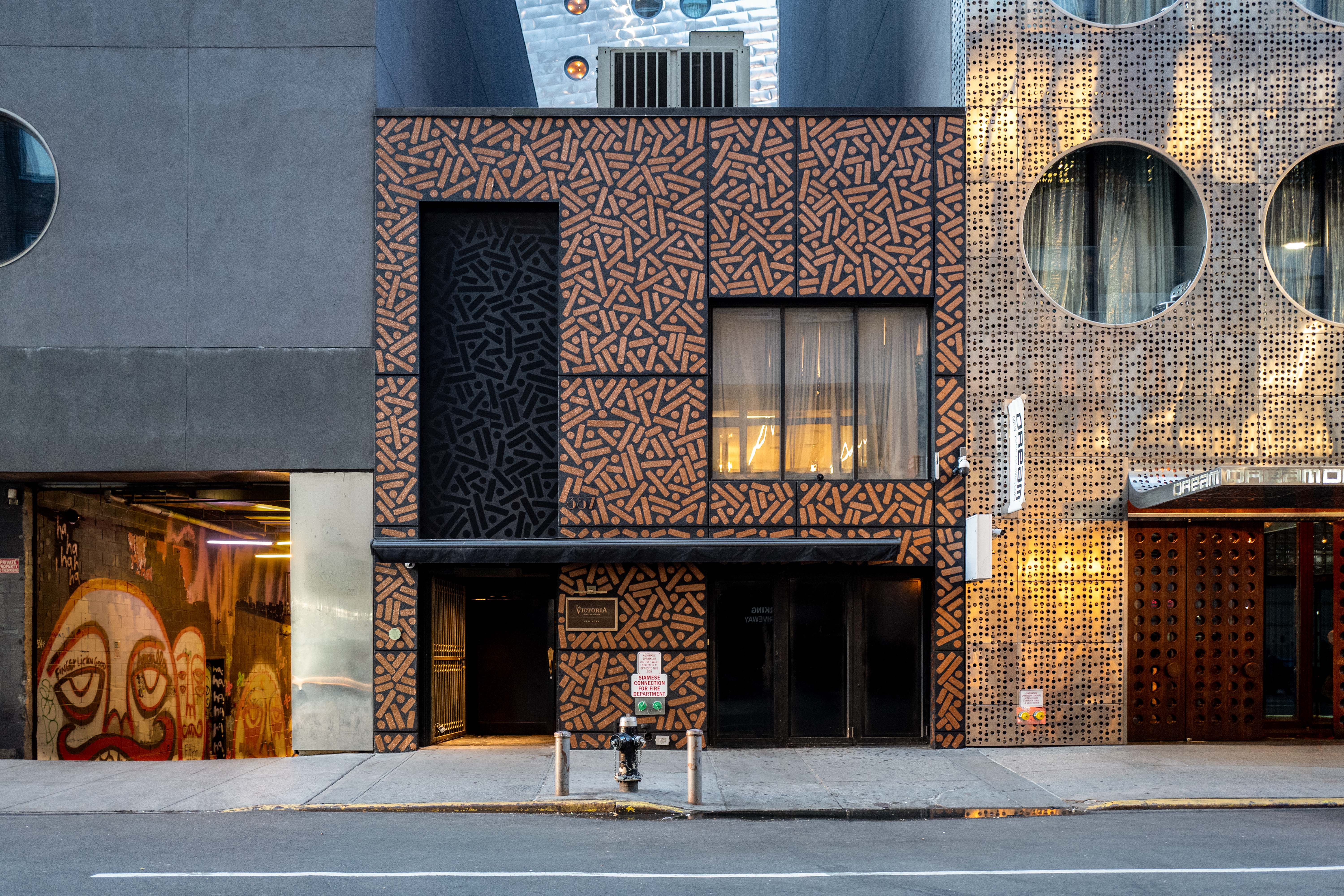 Dark storefront and golden patterned facade with circular upper windows viewed from across the street.