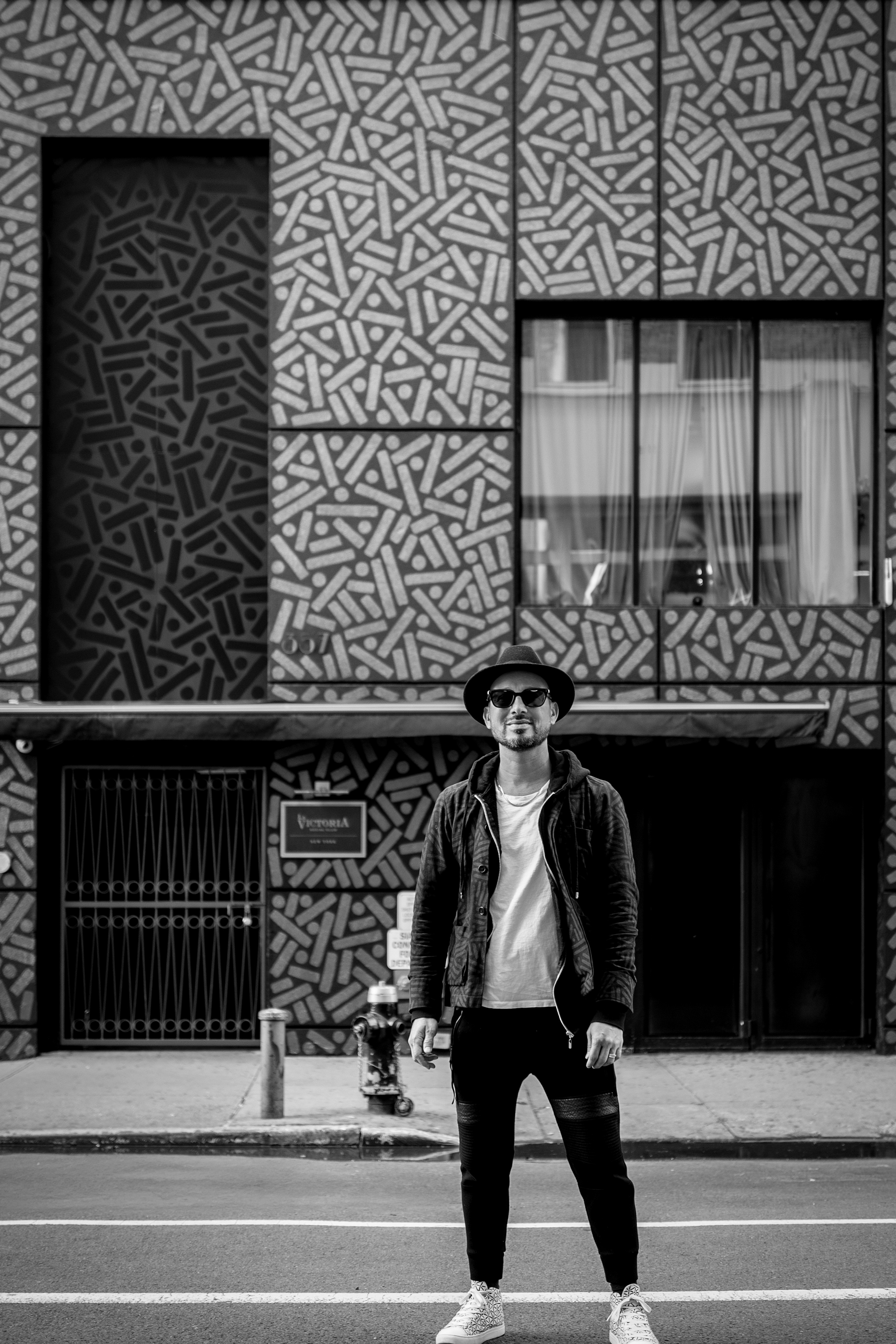 The Golden Weave: Black-and-white portrait of a person standing below a patterned storefront facade.